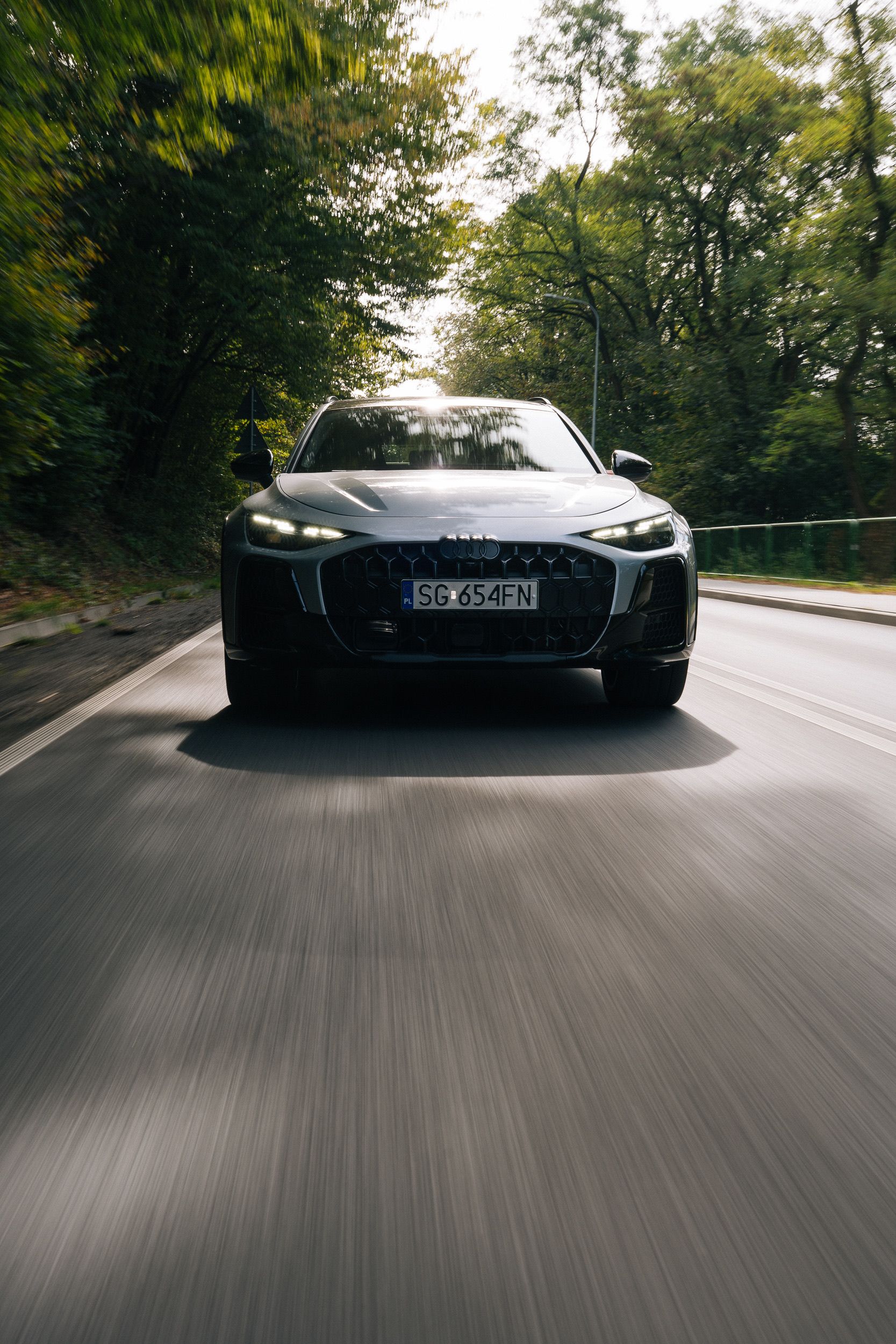Srebrne Audi na wprost, pod kołami rozmyty asfalt — kadr car-to-car