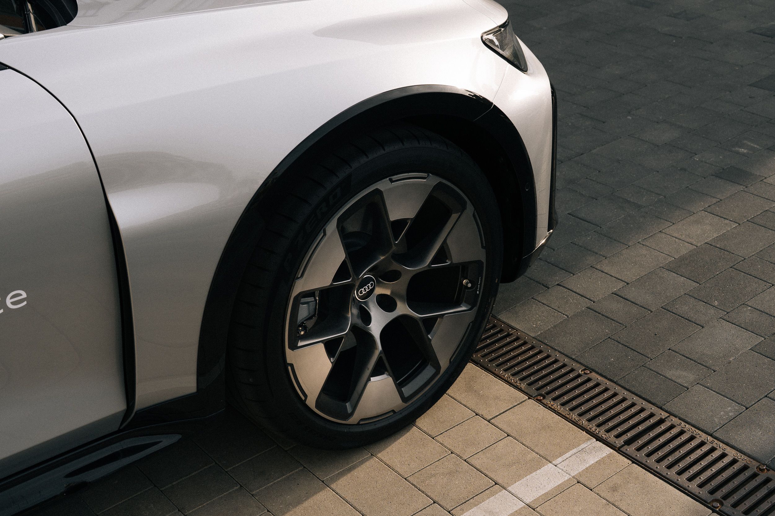 Detal: felga i błotnik srebrnego Audi na kostce brukowej