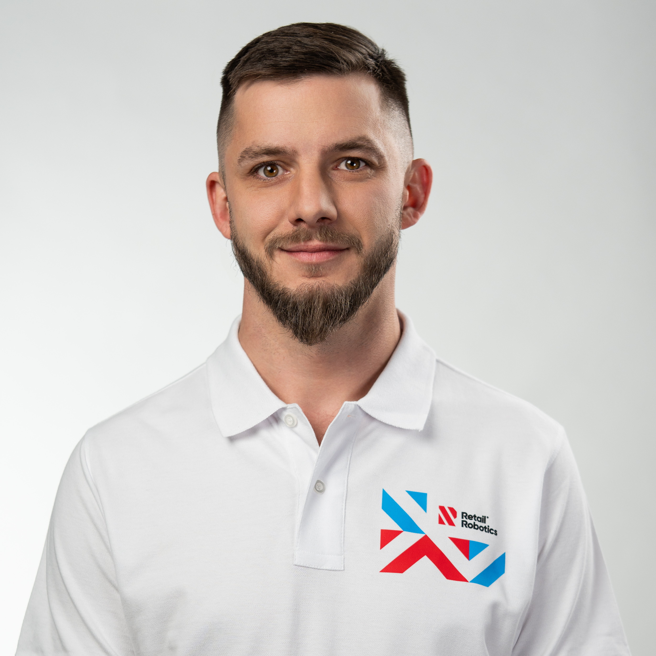 Mężczyzna w białym polo z logo Retail Robotics — portret biznesowy, sesja w Tychach